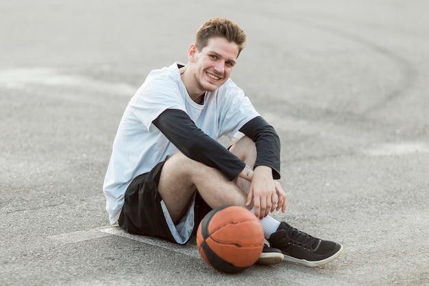 Foto gratuita hombre sentado con una pelota de baloncesto