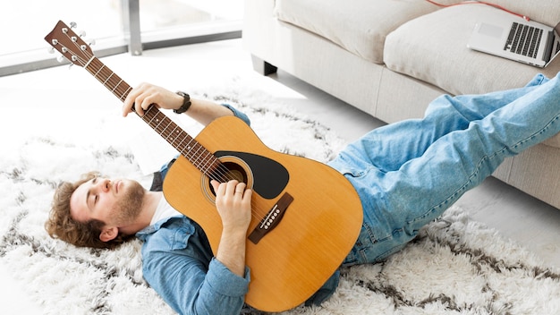 Hombre sentado en el piso y tocando la guitarra