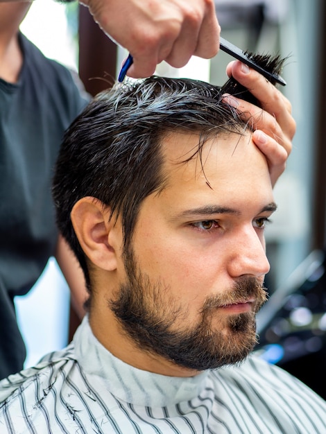 Foto gratuita hombre sentado quieto y cortándose el pelo