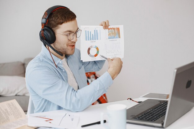 Hombre sentado en la sala de estar en casa. Chico disfruta estudiando con ordenador portátil y auriculares.