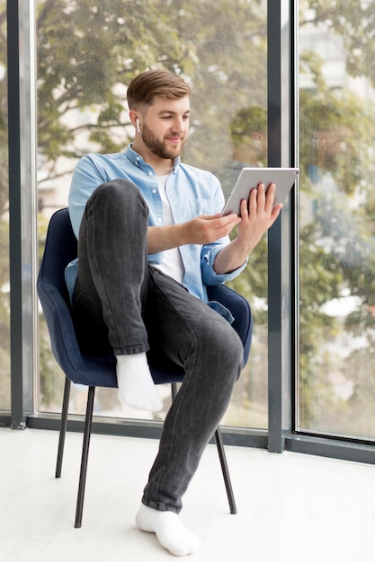 Foto gratuita hombre sentado en la silla con tableta