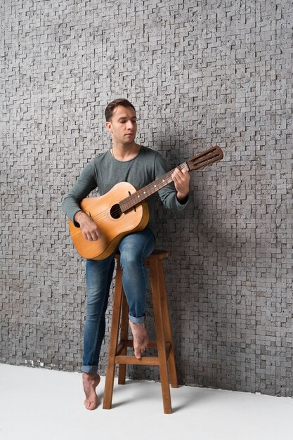 Hombre sentado en una silla tocando la guitarra clásica