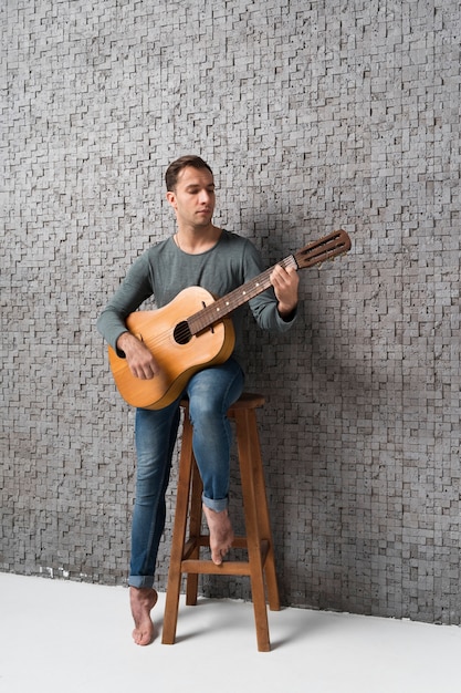 Hombre sentado en una silla tocando la guitarra clásica