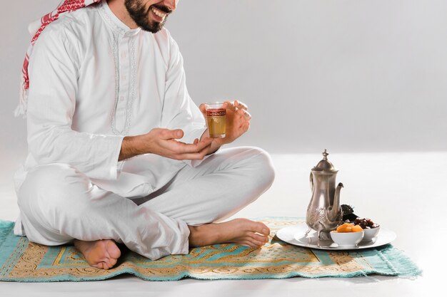Hombre sentado y sosteniendo una taza de té árabe