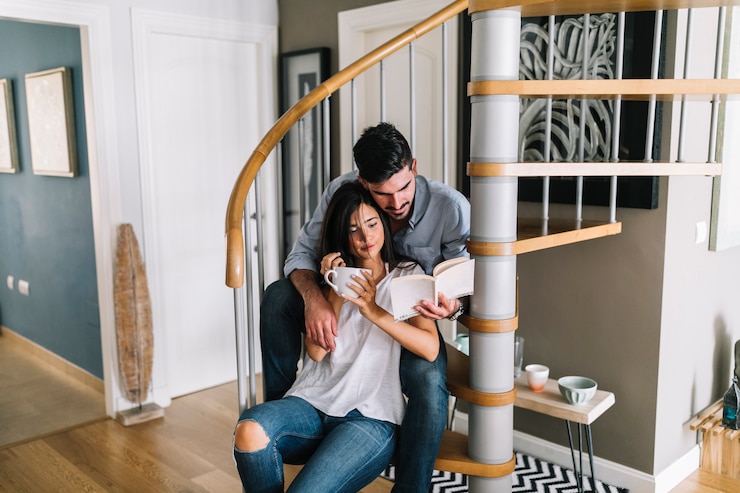 Foto gratuito hombre sentado con su novia sentado en el libro de lectura de la escalera