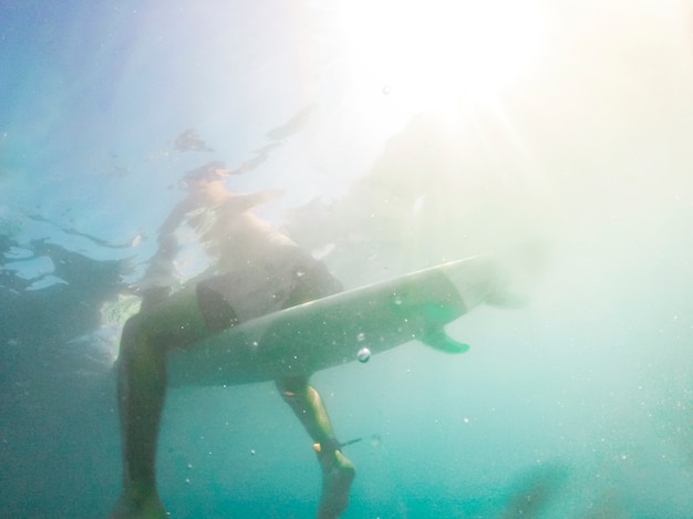 Hombre sentado en la tabla de surf en agua azul