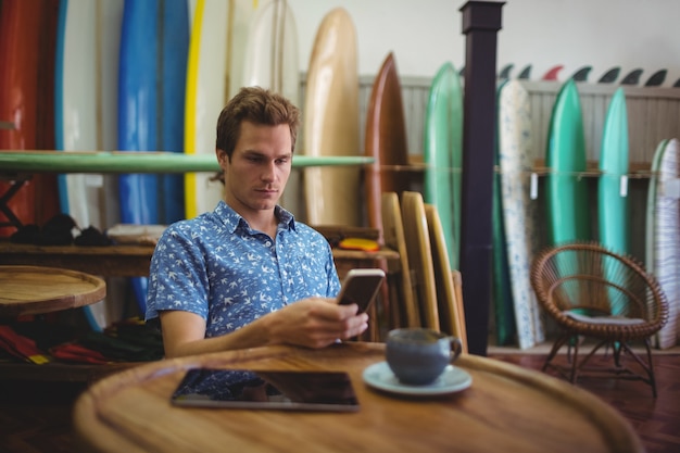 Foto gratuita hombre sentado en la tienda de tablas de surf