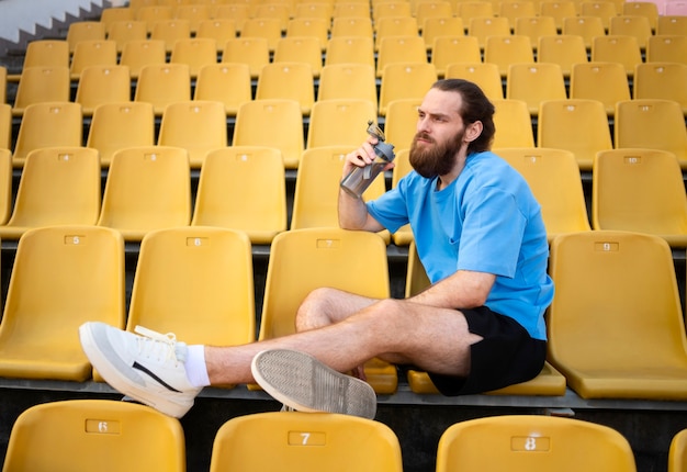 Foto gratuita hombre sentado en las tribunas tiro completo