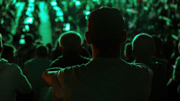 Hombre sentado viendo fútbol en un lugar público por la noche