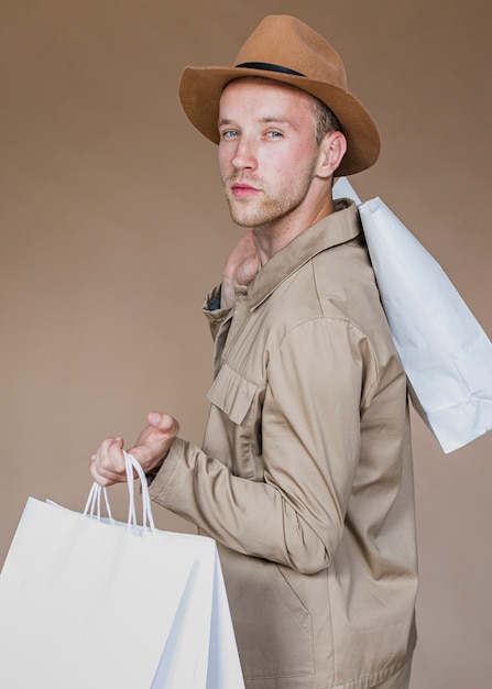 Hombre serio con bolsas de compras mirando a la cámara