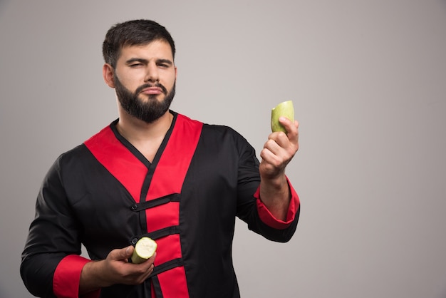 Hombre serio con calabacín medio cortado en pared gris