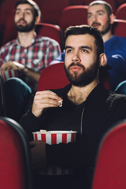Hombre serio comiendo palomitas de maíz en el cine