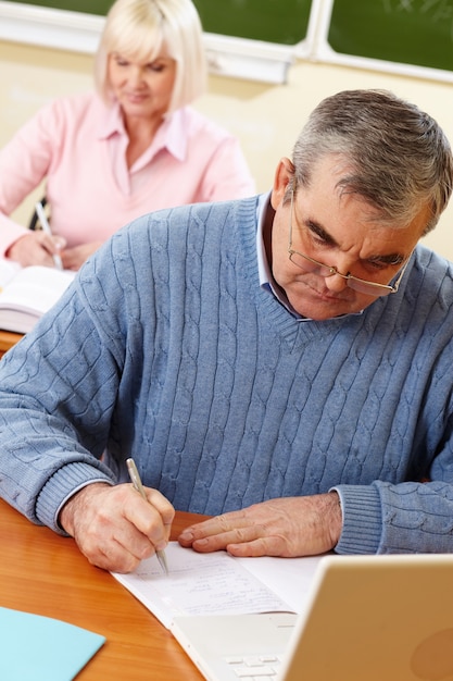 Hombre serio escribiendo en su cuaderno