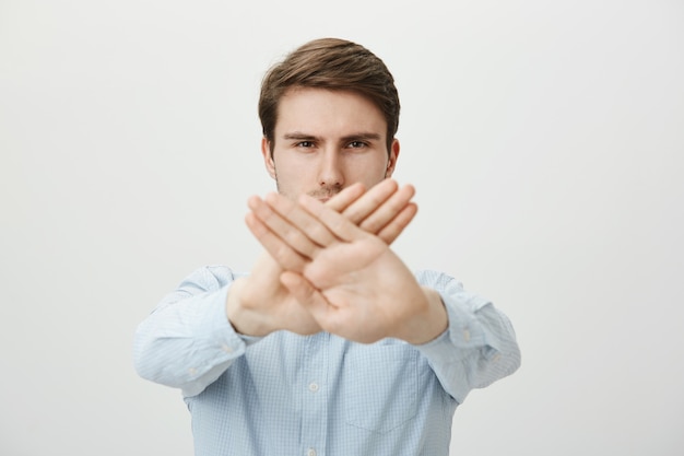 Hombre serio mostrando gesto de parada, restringir o prohibir la acción