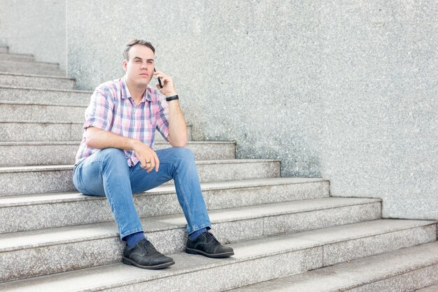 Hombre serio que llama en Smartphone en la escalera de la ciudad