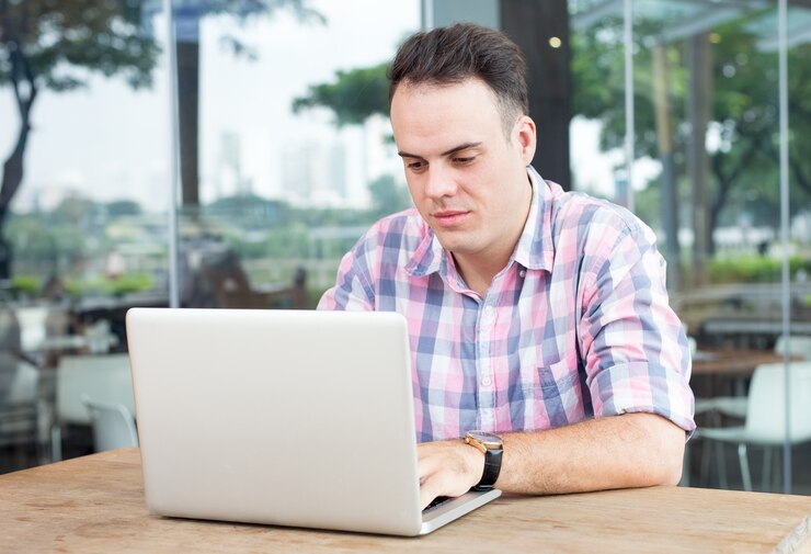 Foto gratuito hombre serio que trabaja en la computadora portátil en el café al aire libre