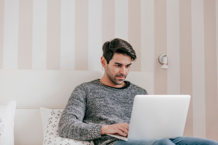 Foto gratuito hombre serio que usa la computadora portátil en cama