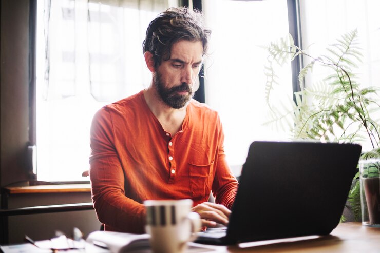 Foto gratuito hombre serio que usa la computadora portátil en el lugar de trabajo