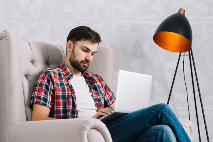 Foto gratuito hombre serio que usa la computadora portátil en el sillón