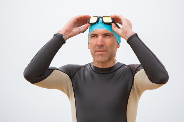 Hombre serio en traje de neopreno con gafas