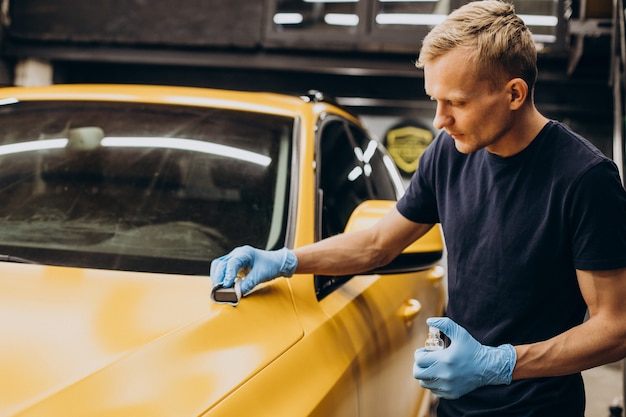 Hombre en servicio de coche haciendo procedimiento de cerámica de coche