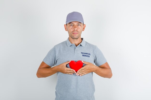 Hombre de servicio técnico con corazón rojo en camiseta gris con gorra