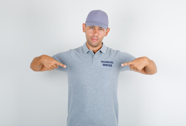 Hombre de servicio técnico mostrándose en camiseta gris con gorra y mirando confiado