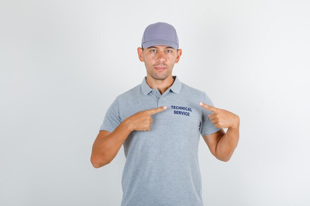 Hombre de servicio técnico que muestra texto en uniforme en camiseta gris con gorra