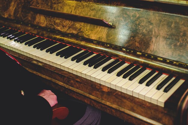 El hombre se sienta en un viejo piano de época