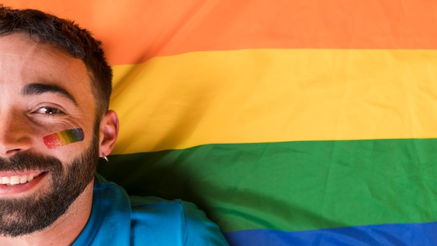 Hombre con símbolo de arcoiris lgbt en cara sobre fondo multicolor