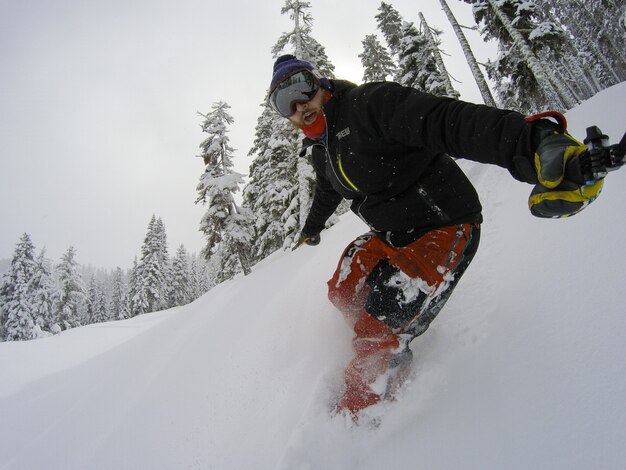 Hombre de snowboarder tomando selfie en acción