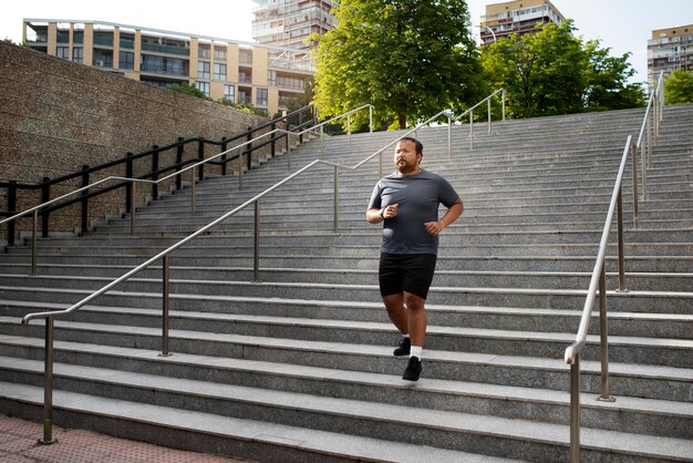 Hombre con sobrepeso haciendo ejercicio en las escaleras al aire libre