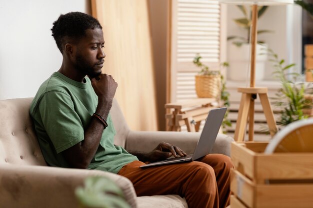 Hombre en el sofá haciendo un plan para redecorar casa usando laptop