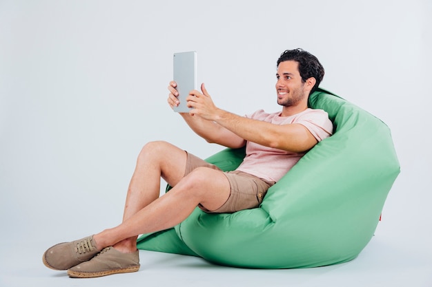 Hombre en sofá haciendo un selfie con tablet