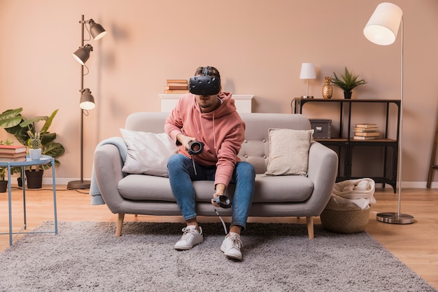 Hombre en el sofá jugando con auriculares virtuales