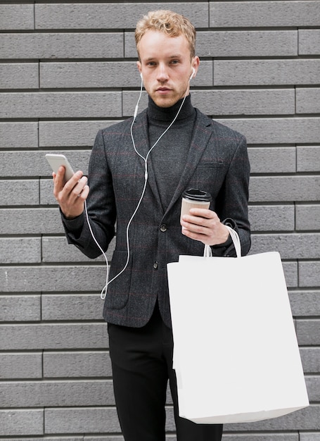 Hombre solitario con bolsas de compras y teléfono inteligente