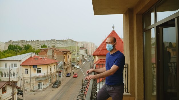 Hombre solitario con máscara en la terraza durante el aislamiento del coronavirus.