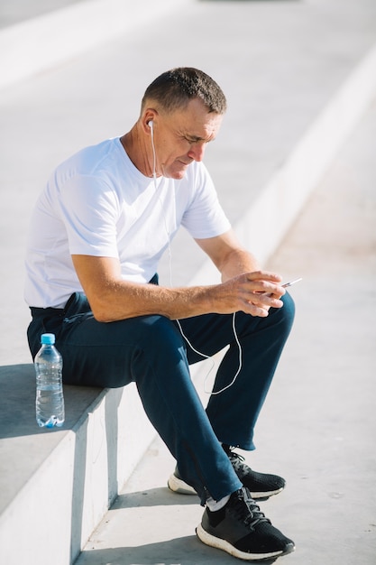 Hombre solitario sentado con un teléfono inteligente en sus manos