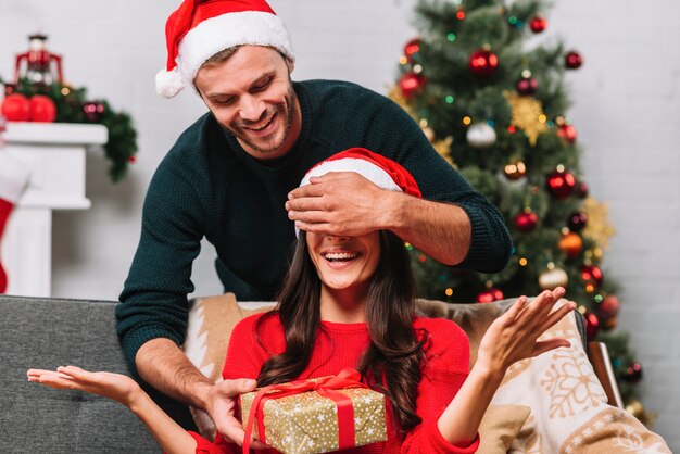 Hombre en sombrero de fiesta cerrando los ojos a mujer feliz