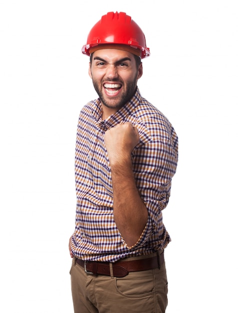 Hombre sonriendo con un casco rojo y un puño levantado