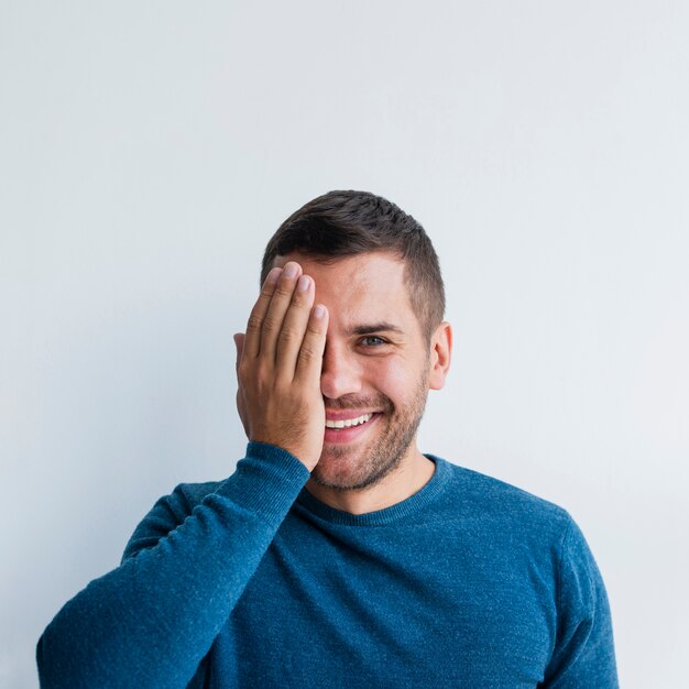 Hombre sonriendo y cubriendo media cara con una mano