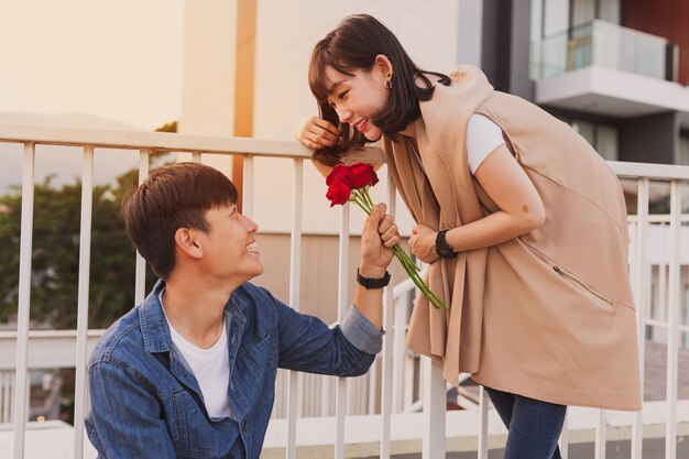 Hombre sonriendo entregando rosas a una mujer