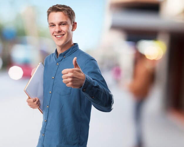 Hombre sonriendo con una libreta y el pulgar levantado