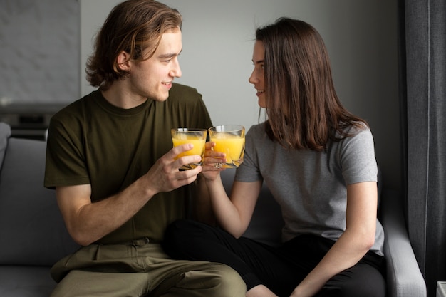 Foto gratuita hombre sonriendo a novia mientras sostiene un vaso de jugo de naranja