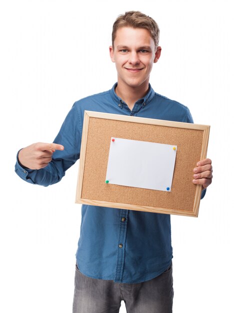 Hombre sonriendo con un papel en blanco en un tablón