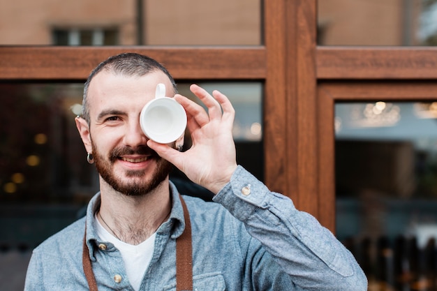 Hombre sonriendo y posando con una taza de café