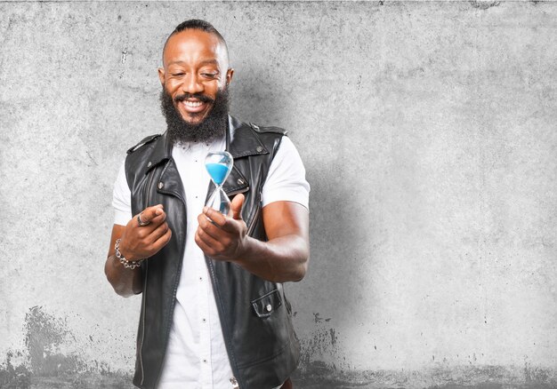 Hombre sonriendo con un reloj de arena en una mano