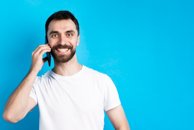 Hombre sonriendo y sosteniendo el teléfono inteligente al oído