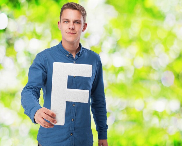 Hombre sonriendo sujetando la letra "f"