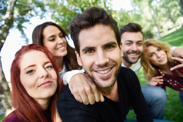 Hombre sonriendo tomando una auto foto de el y sus amigos con árboles de fondo